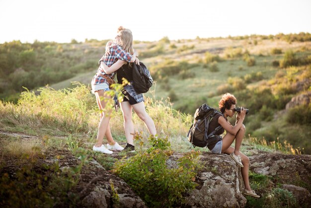 Chicas sonriendo, abrazándose, sentados en la roca, disfrutando de la vista en el cañón