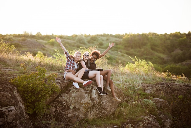 Foto gratuita chicas sonriendo, sentados en roca, disfrutando de la vista en el cañón