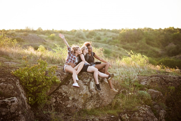 Chicas sonriendo, sentados en roca, disfrutando de la vista en el cañón