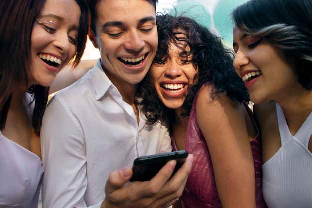 Chicas sonrientes de ángulo bajo mirando el teléfono