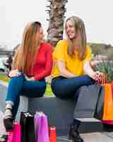 Foto gratuita chicas sonrientes con bolsas de compras mirándose