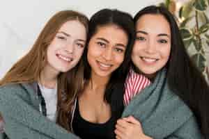 Foto gratuita chicas sonrientes cubiertas con tela escocesa mirando a cámara