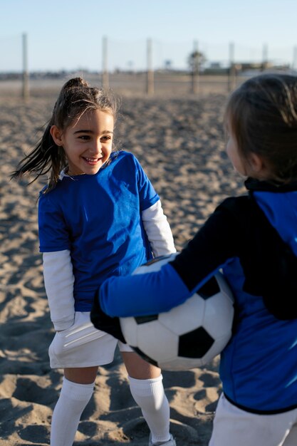 Chicas sonrientes con fútbol en la playa