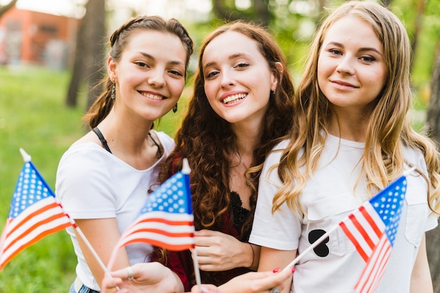 Chicas sonrientes en la naturaleza con banderas americanas