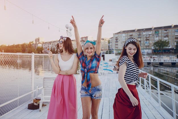 Chicas sonrientes en un puerto y una con los brazos en alto