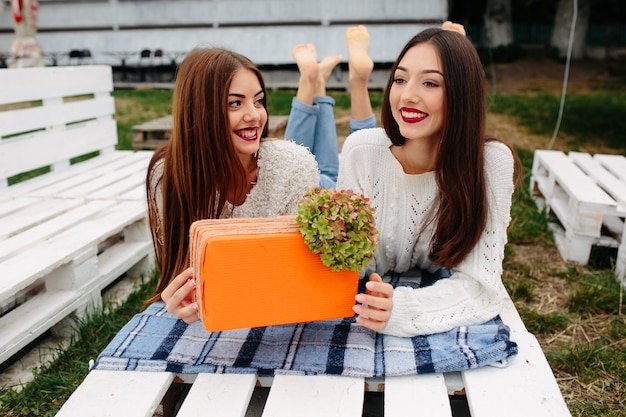 Chicas sonrientes con un regalo naranja