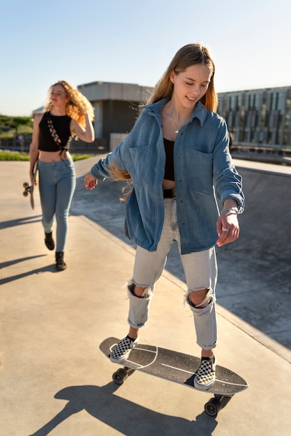 Chicas sonrientes de tiro completo con patineta