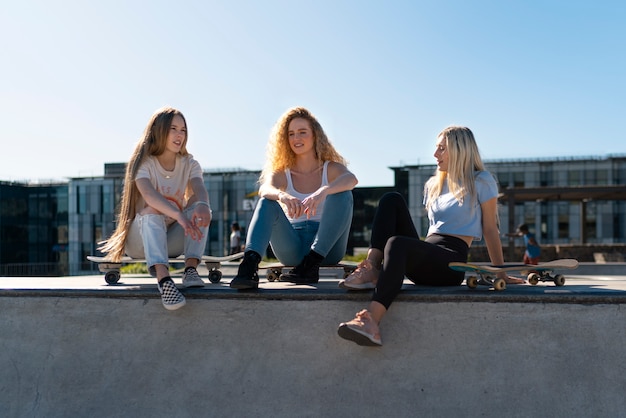 Foto gratuita chicas sonrientes de tiro completo con patinetas