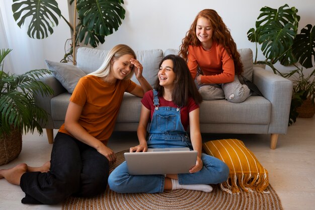 Chicas sonrientes de tiro completo sentadas en el interior