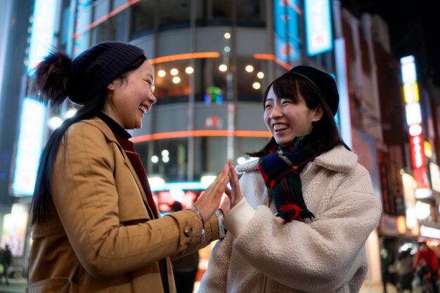 Chicas sonrientes en tiro medio de la ciudad