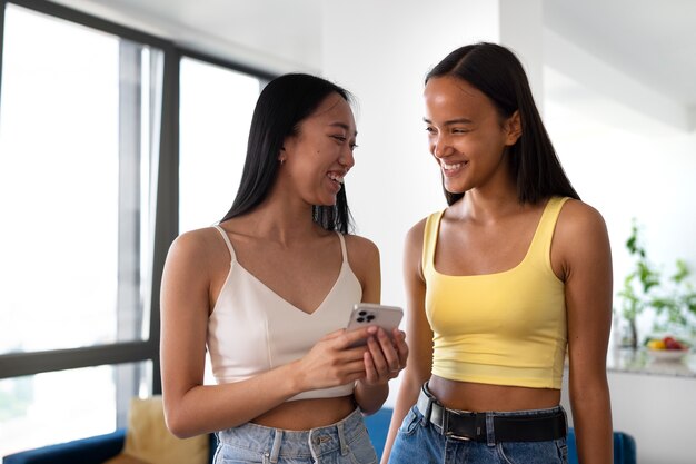 Chicas sonrientes de tiro medio con teléfono inteligente