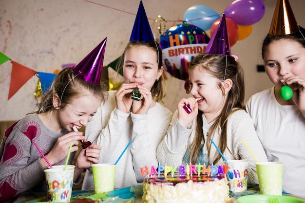 Chicas soplando cuernos de fiesta