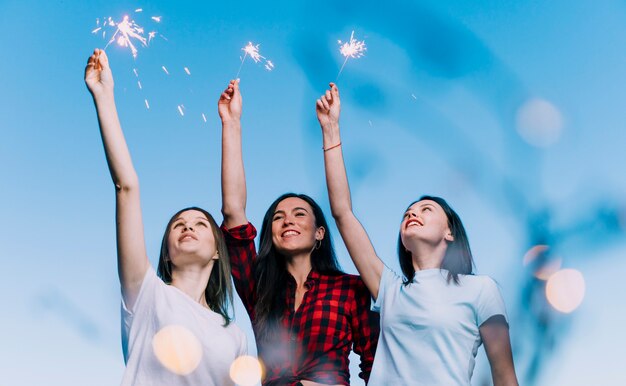 Chicas sosteniendo fuegos artificiales en la azotea al amanecer