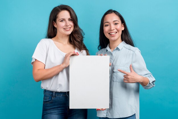 Chicas sujetando tablón en blanco