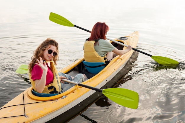 Chicas de tiro completo remando en kayak