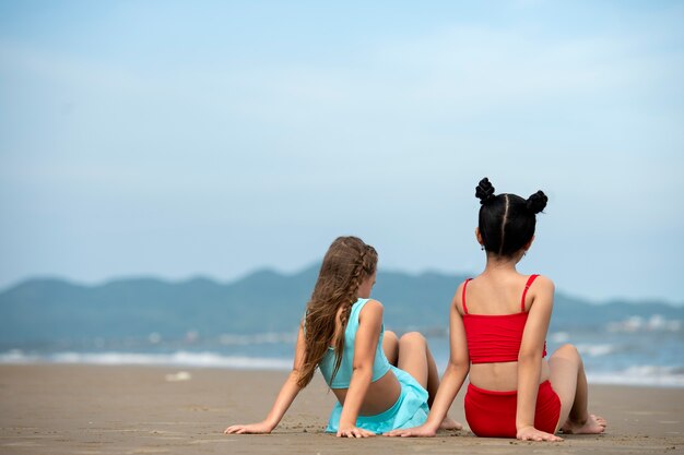 Chicas de tiro completo sentadas en la playa