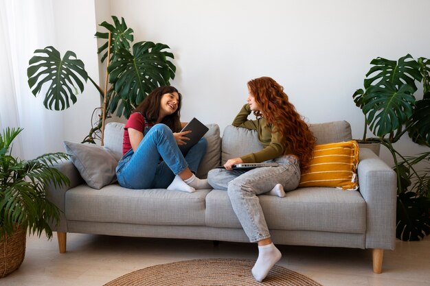 Chicas de tiro completo sentadas en el sofá