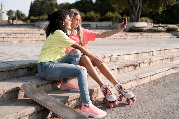 Foto gratuita chicas de tiro completo tomando selfie juntos