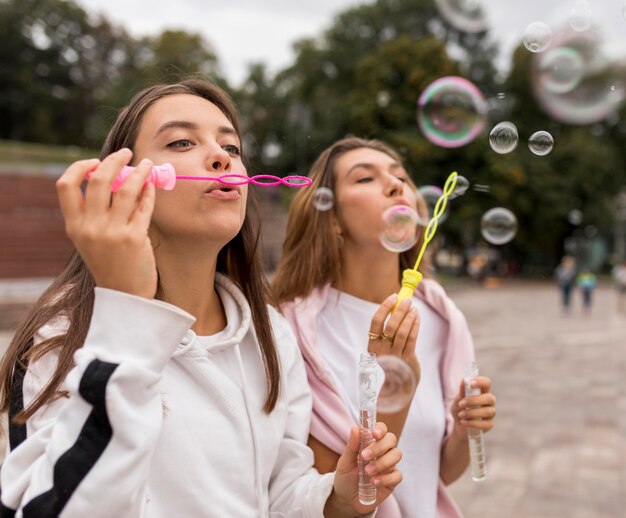 Chicas de tiro medio haciendo globos de jabón