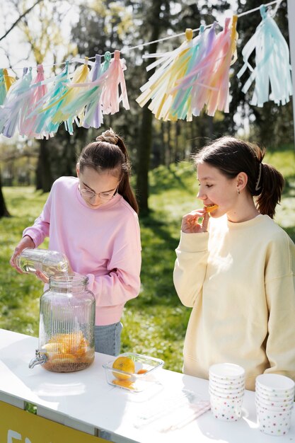 Chicas de tiro medio haciendo limonada fresca.