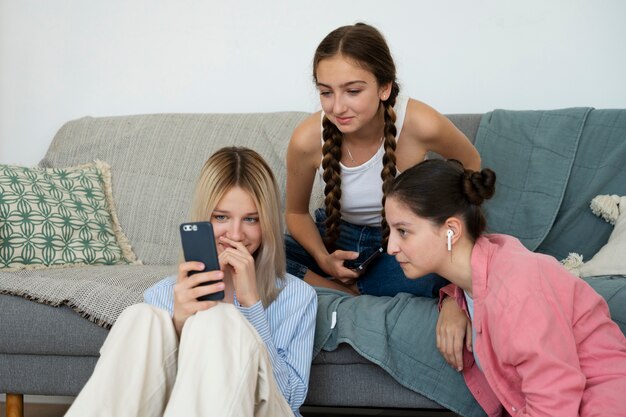 Chicas de tiro medio mirando el teléfono inteligente