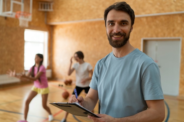 Foto gratuita chicas de tiro medio y profesor en el gimnasio de la escuela