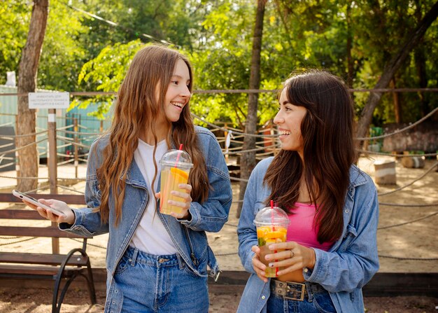 Chicas de tiro medio sosteniendo jugo fresco