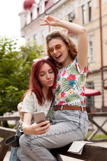 Chicas de tiro medio tomando selfie en el centro de la ciudad