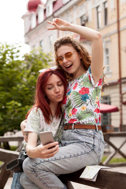 Chicas de tiro medio tomando selfie en el centro de la ciudad