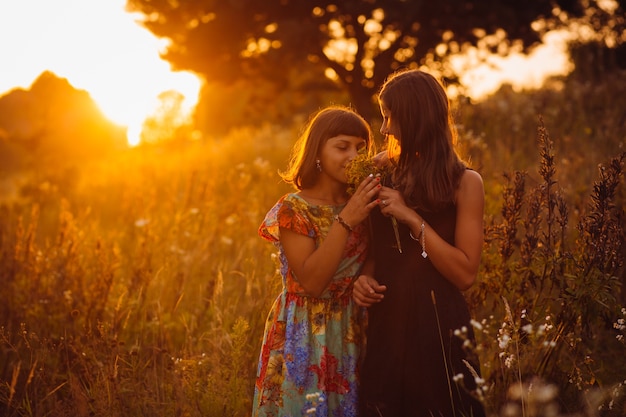 Chicas tranquilas se paran en el campo de la tarde