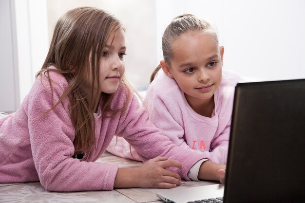 Chicas usando la computadora portátil en el piso