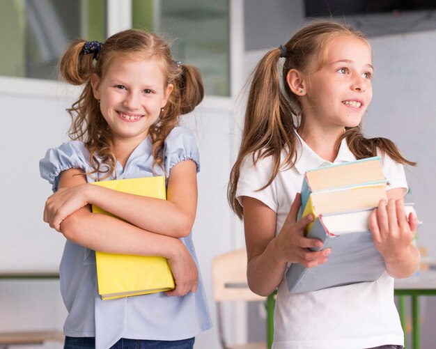 Chicas de vista frontal sosteniendo libros en clase