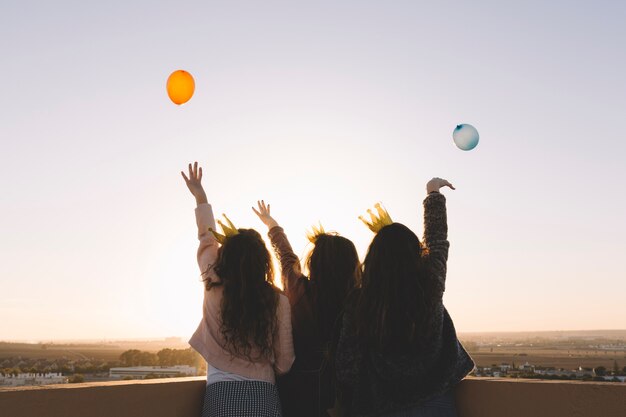 Chicas de vista trasera arrojando globos desde el techo