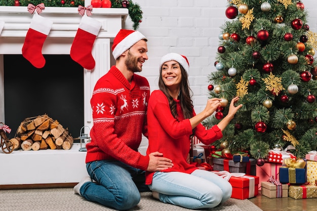 Chico abrazando a la señora decorando el árbol de Navidad con adornos