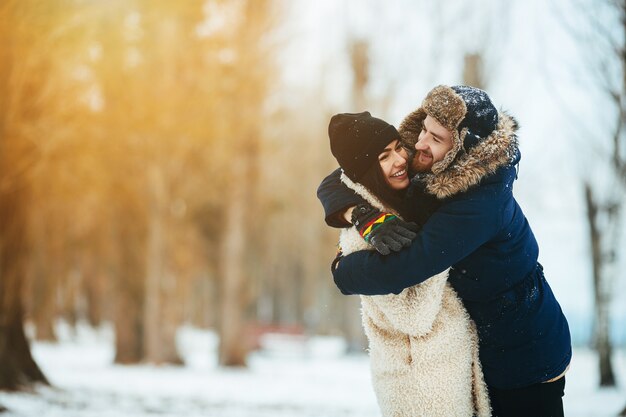 Chico abrazando a su novia en un parque nevado