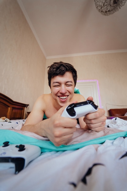 Chico acostado en la cama y jugando videojuegos