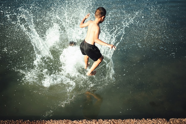 Chico activo saltando en el agua