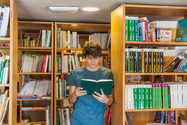 Chico adolescente disfrutando de leer cerca de librería