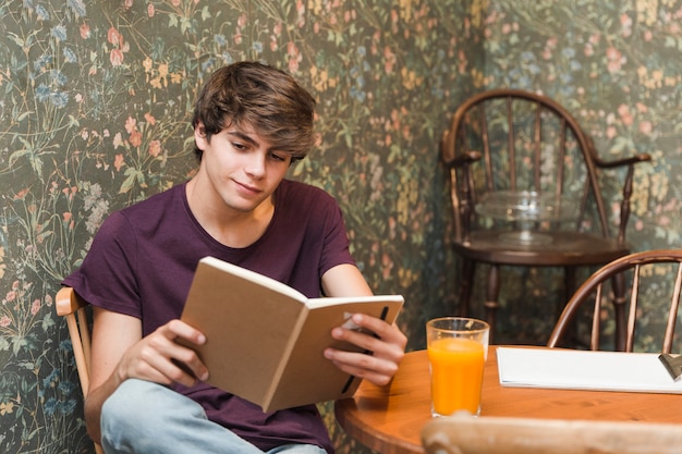 Chico adolescente leyendo en la mesa de café