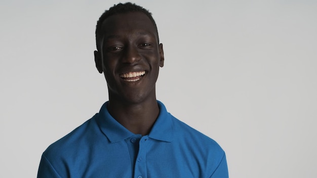 Chico afroamericano sonriente alegre que parece feliz en la cámara sobre fondo blanco Expresión positiva