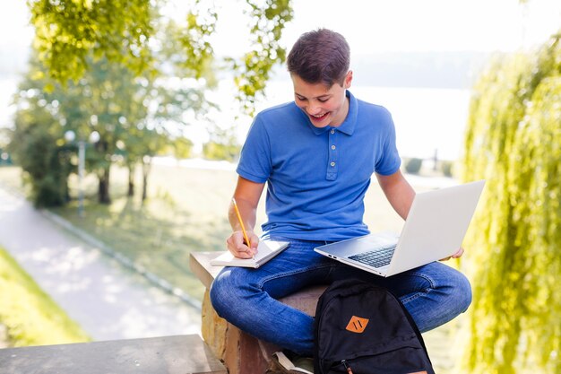 Chico alegre haciendo la tarea en el parque