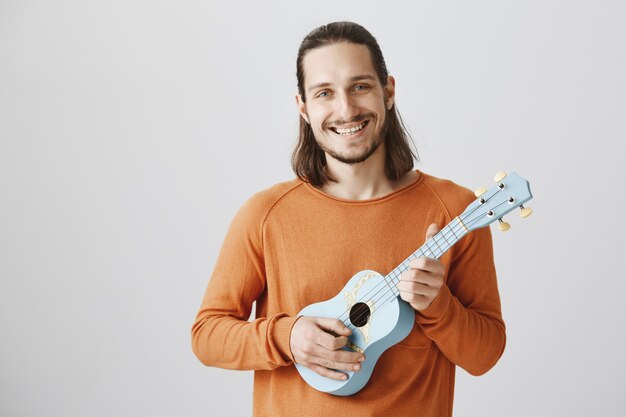 Chico alegre sonriente hipster con ukelele