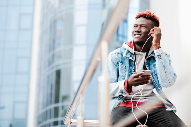 Foto gratuita chico de ángulo bajo con auriculares mirando a otro lado