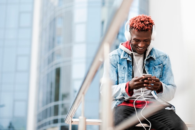 Foto gratuita chico de ángulo bajo con auriculares sonriendo