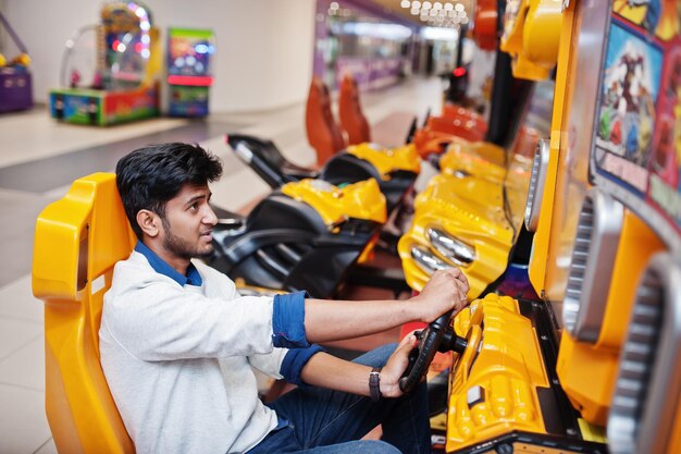 Un chico asiático compite en una máquina simuladora de carreras de juegos arcade de speed rider