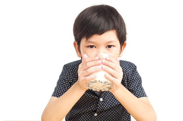 Chico asiático está bebiendo un vaso de leche sobre fondo blanco