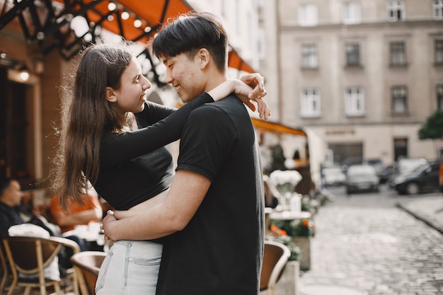 Chico asiático y su novia caucásica en ropa casual de pie en la calle Lviv. Pareja abrazándose mientras caminan juntos en la ciudad