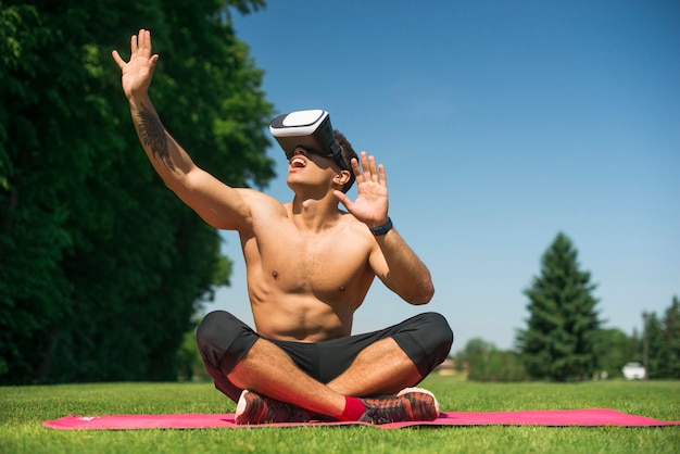 Chico atlético usando unas gafas de realidad virtual al aire libre