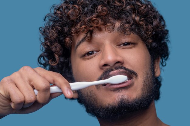 Chico atractivo tranquilo limpiando sus dientes con un cepillo de dientes