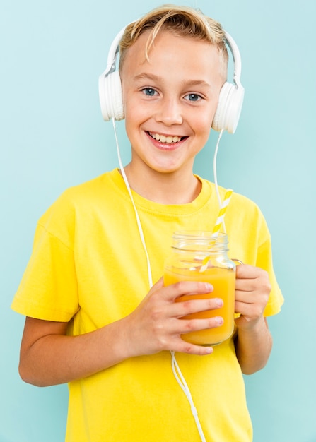 Foto gratuita chico con auriculares bebiendo jugo de naranja